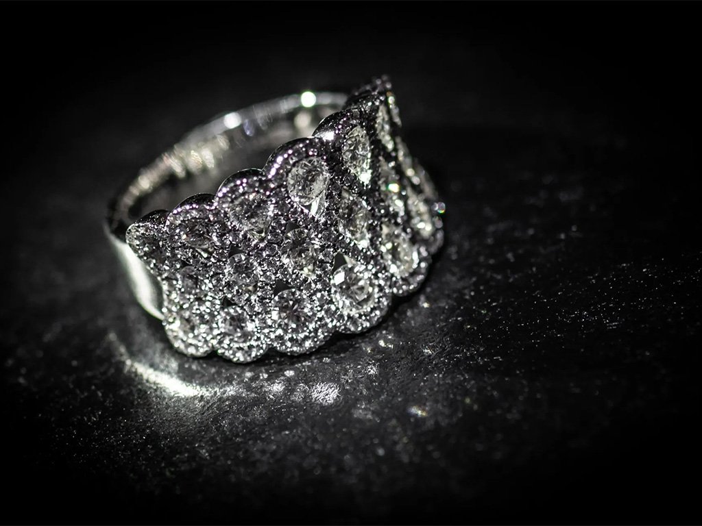 A silver ring with multiple sparkling diamonds on a black surface.