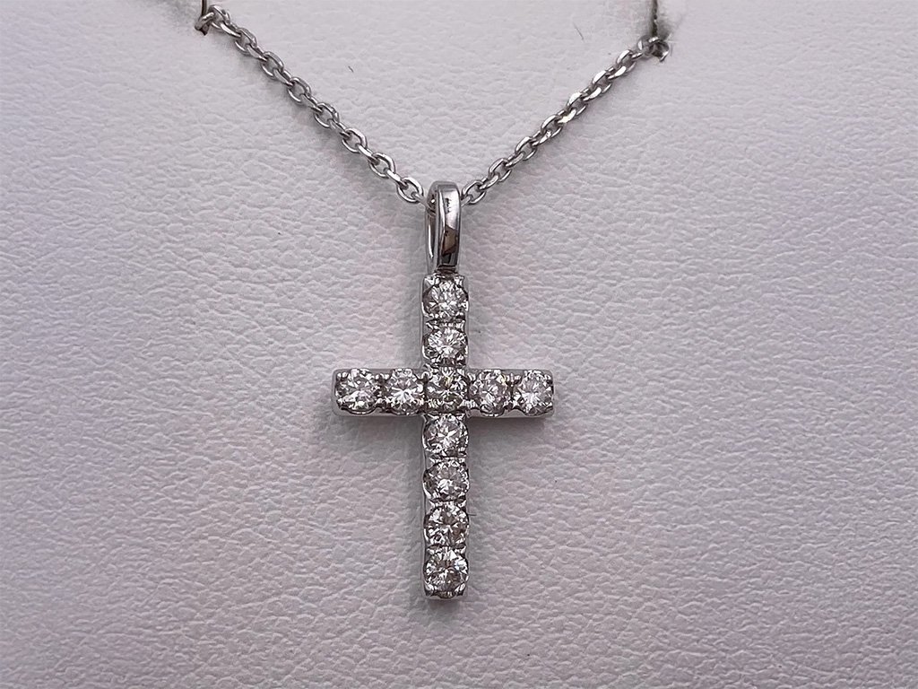 Silver cross pendant encrusted with small diamonds hanging on a silver chain
