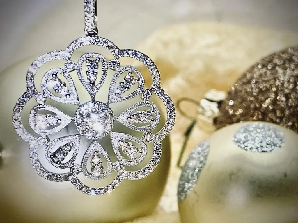 Diamond jewelry surrounded by gold and silver Christmas ornaments.