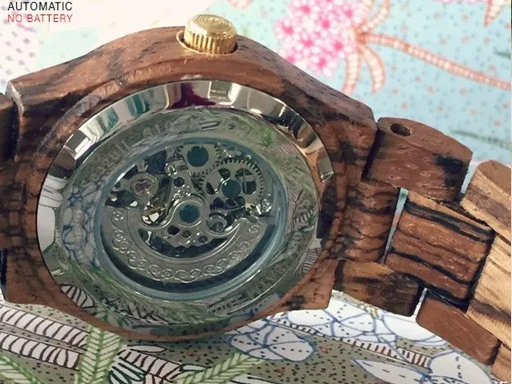 Wooden wristwatch with a transparent face showing the mechanical gears inside.