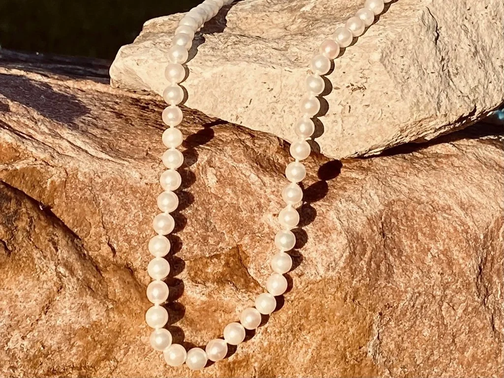 A string of white pearls draped over tan and beige rocks.