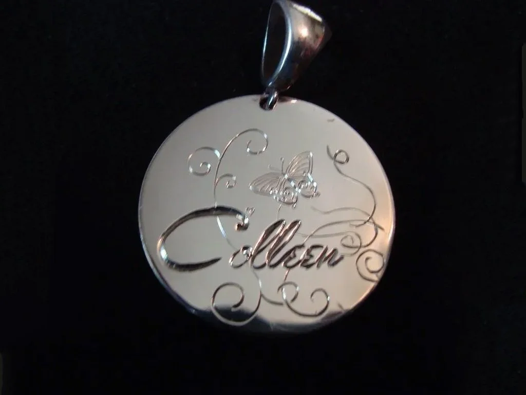 Silver pendant with the name 'Allen' engraved, decorated with a butterfly and floral swirls, hanging from a metal loop.