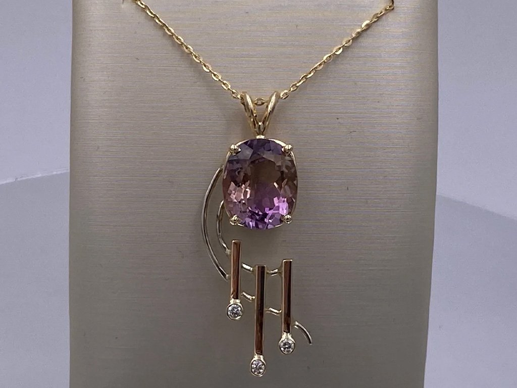 Gold necklace with a large oval purple gemstone pendant and three dangling bars with small clear stones.