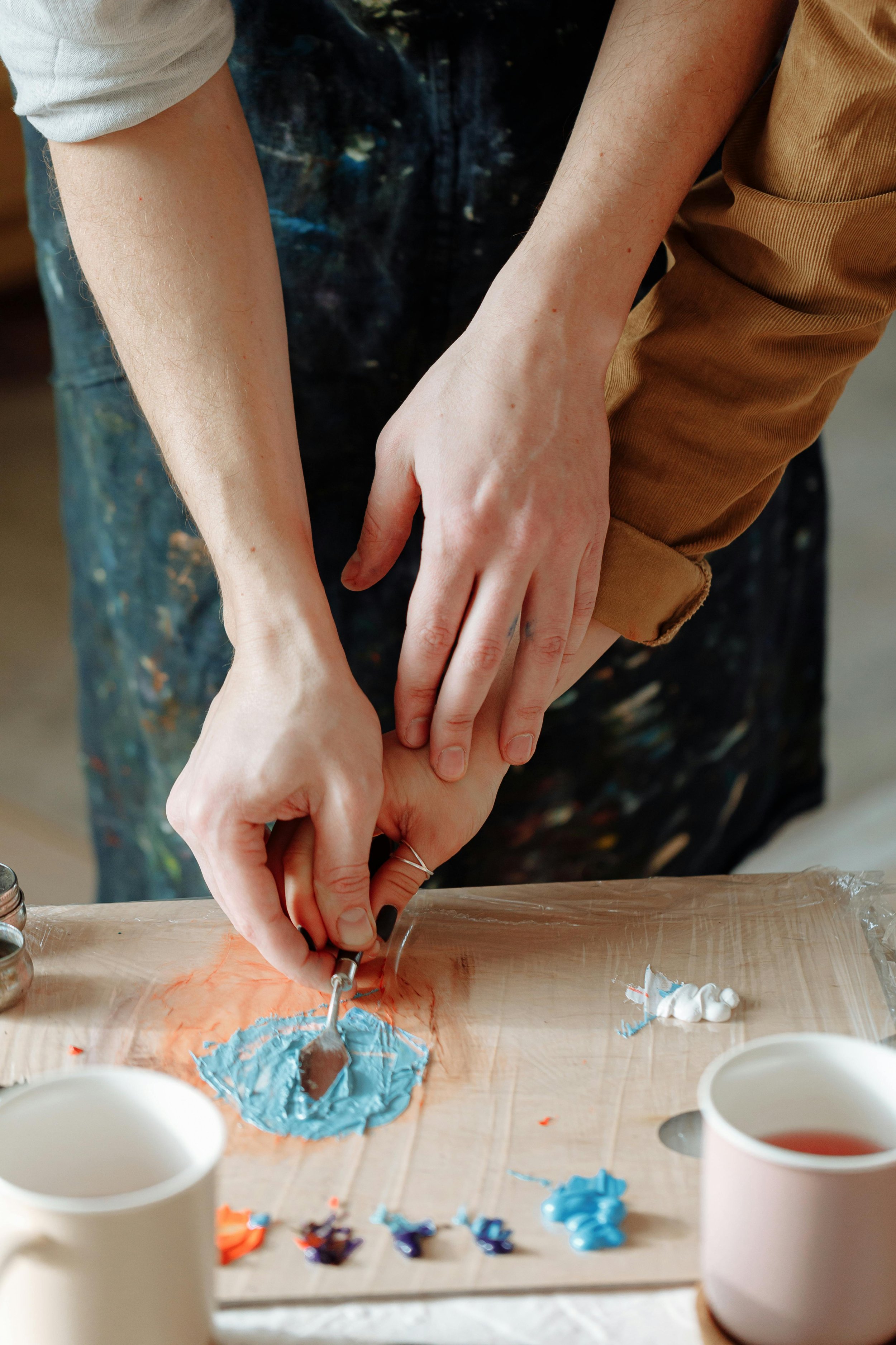 Two people mixing paint together on a canvas, symbolizing practical teamwork and rebuilding partnerships in couples counseling.