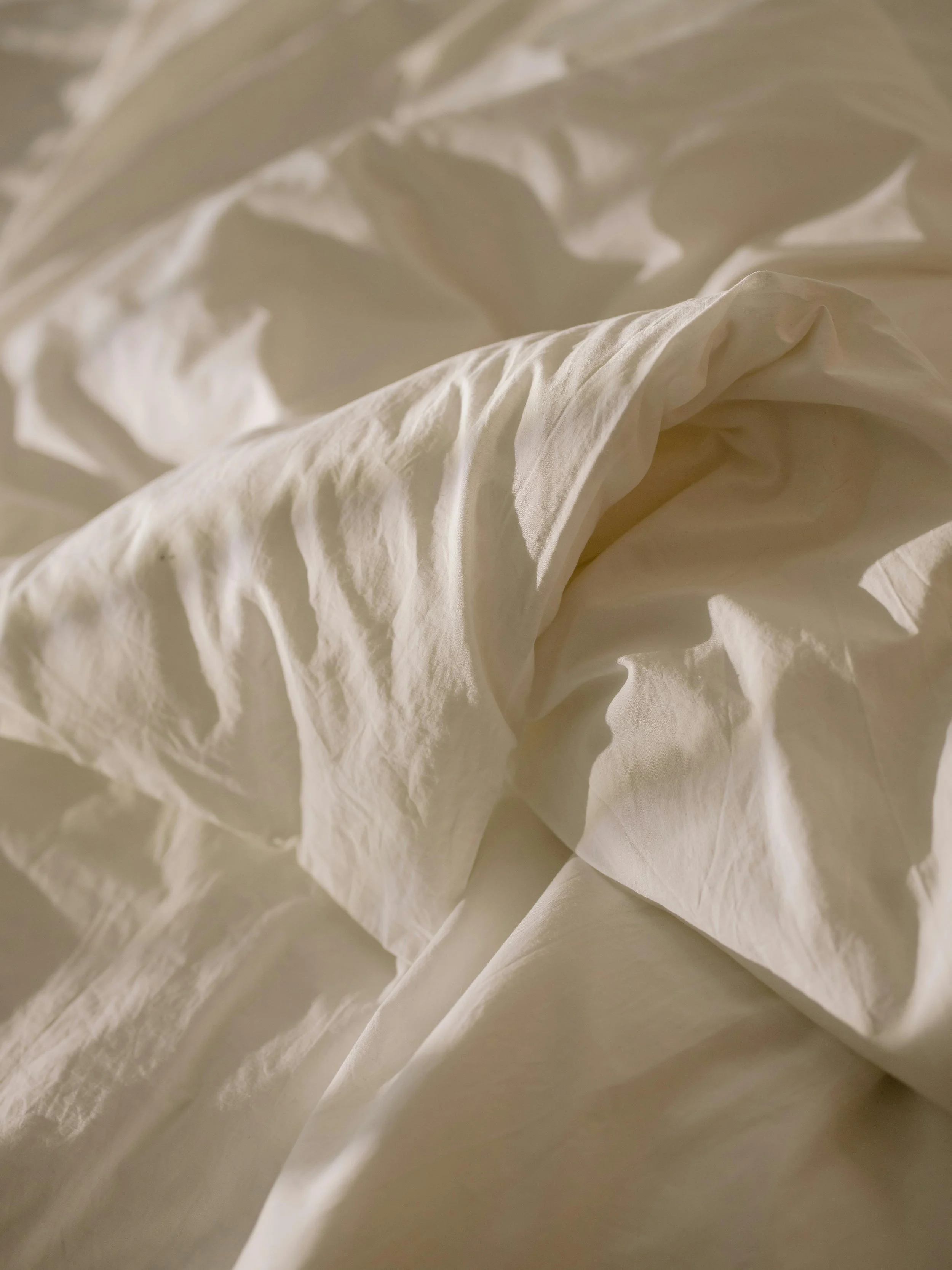 Crumpled white bedsheets, symbolizing physical burnout, severe fatigue, or the weight of chronic stress.