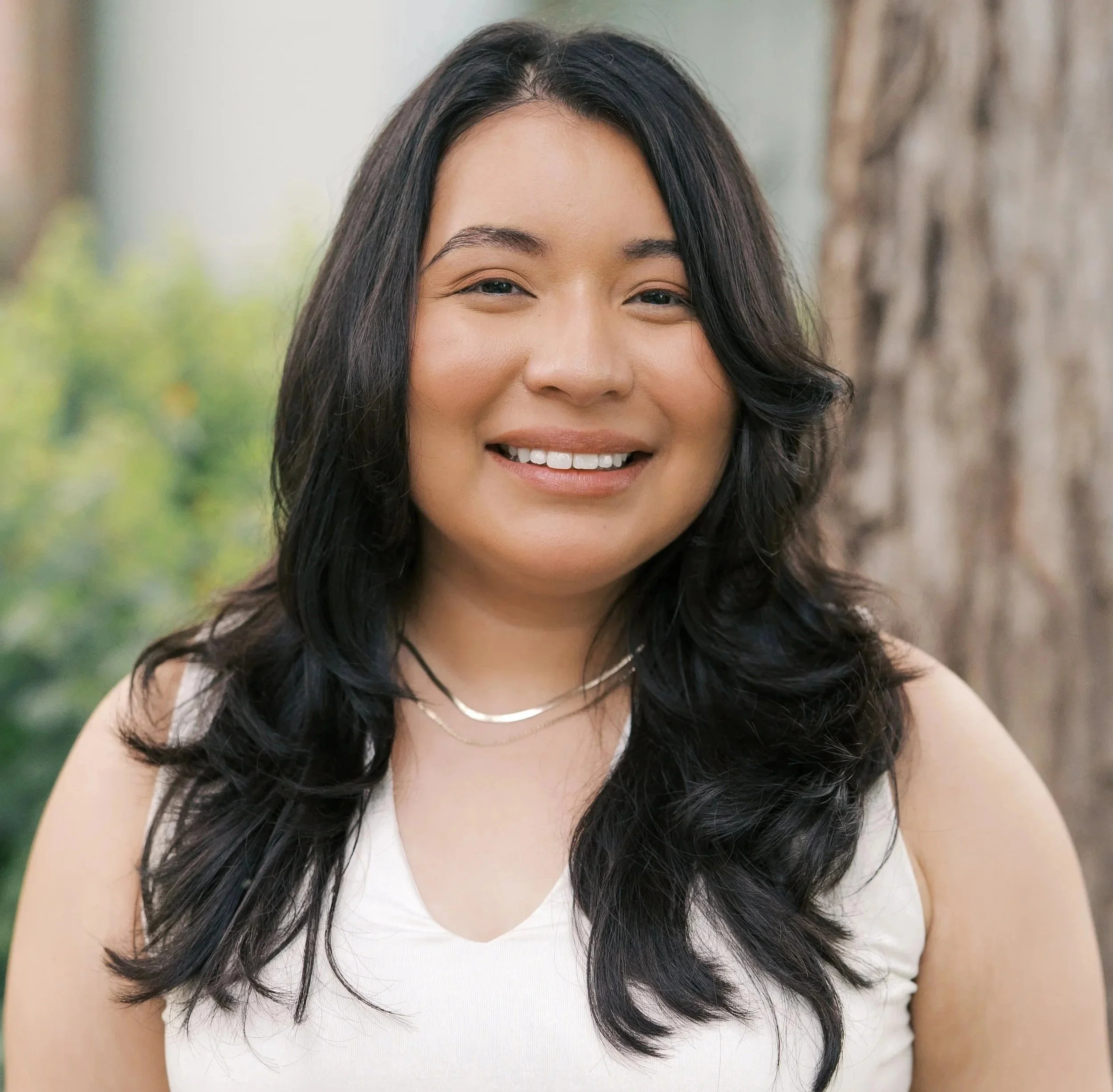 Flor Howell, LMFT-Associate, offering virtual individual and couples therapy throughout Texas, smiling outdoors in The Woodlands.