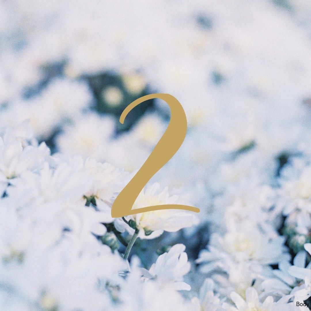 Number 1 in gold font over a blurry background of white flowers and green leaves.