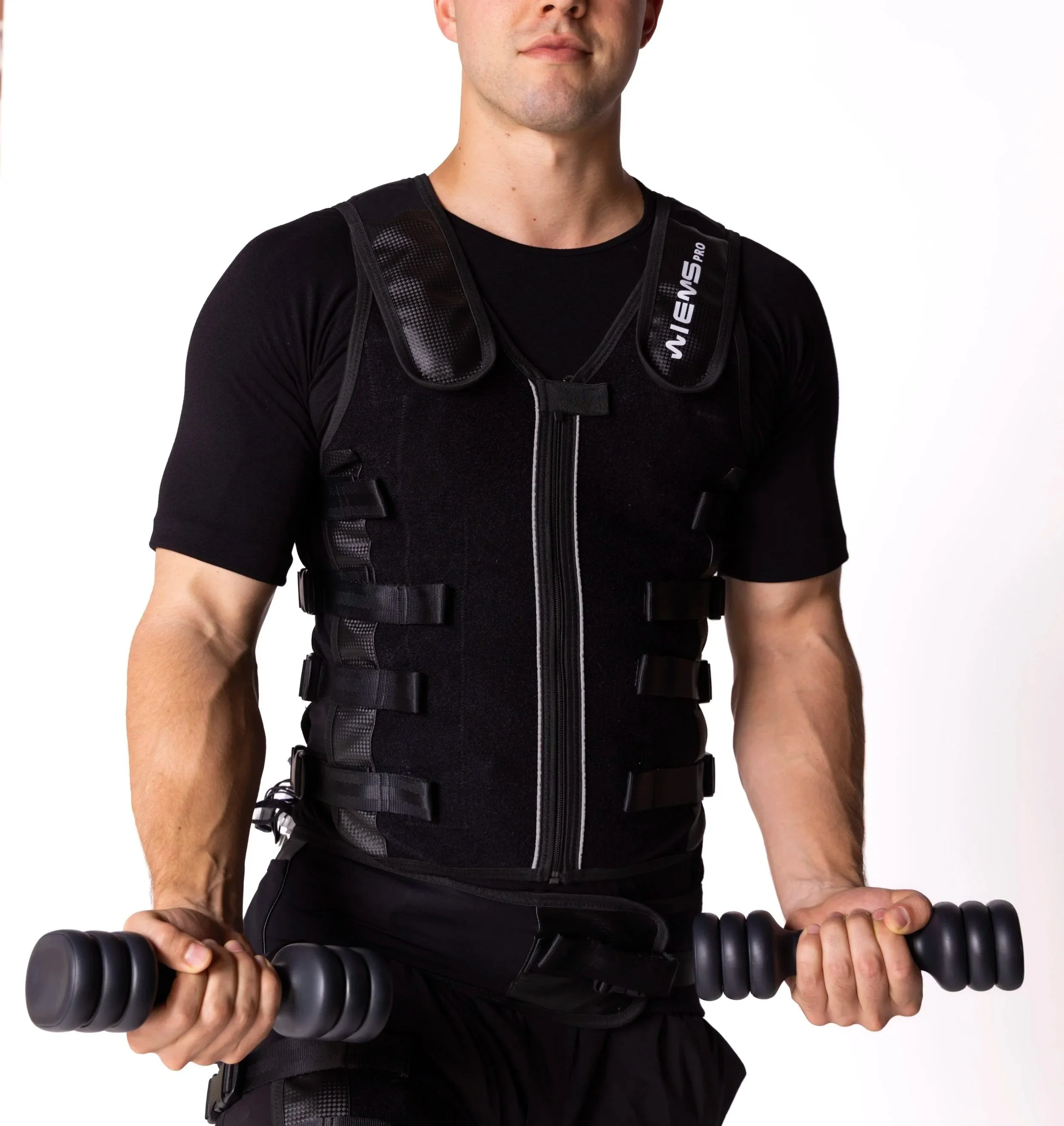 A man wearing a black fitness vest with adjustable straps, holding a black massage roller, standing against a white background.