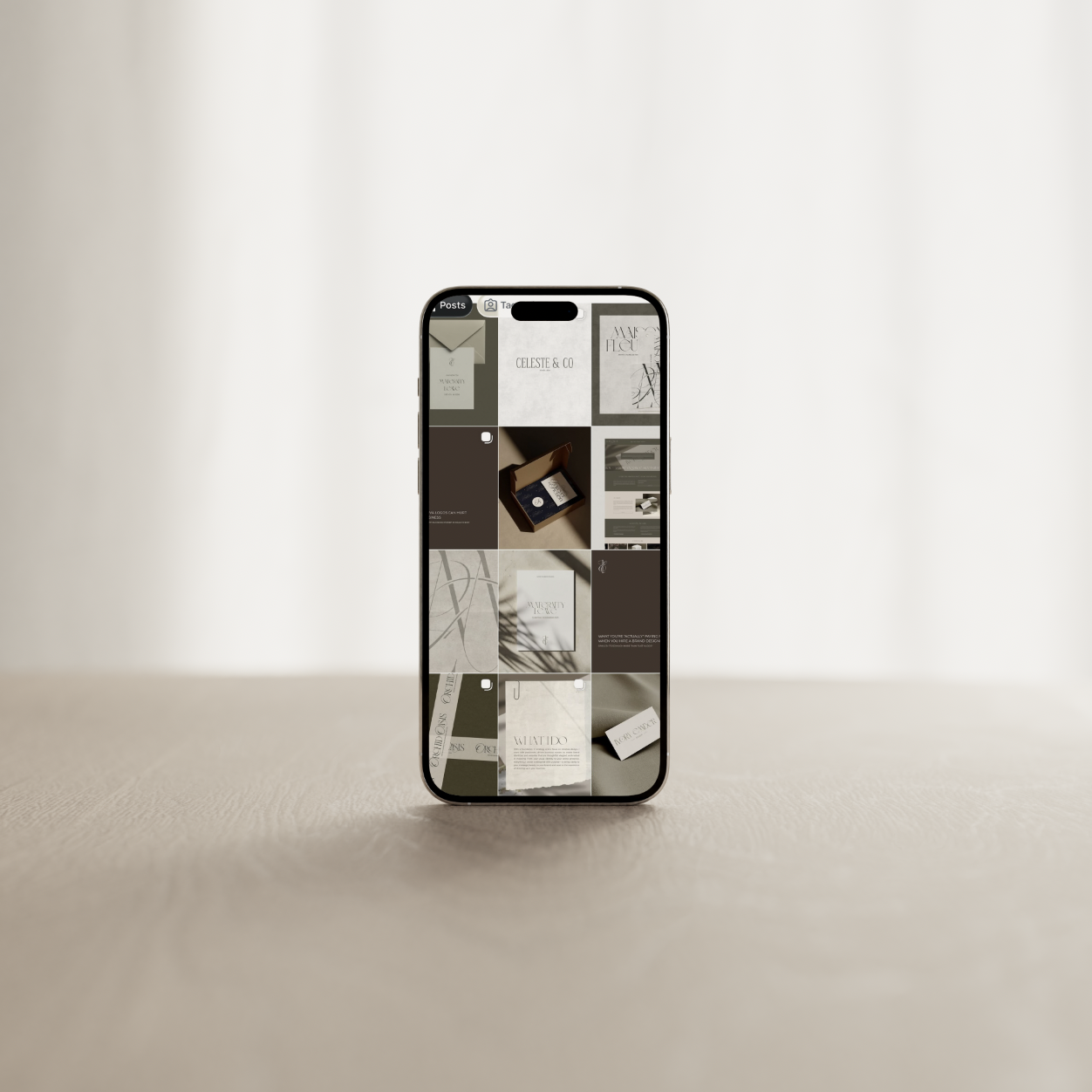 Smartphone displaying a grid of images, mostly of paper products and packaging, placed on a neutral surface with a minimalist background.