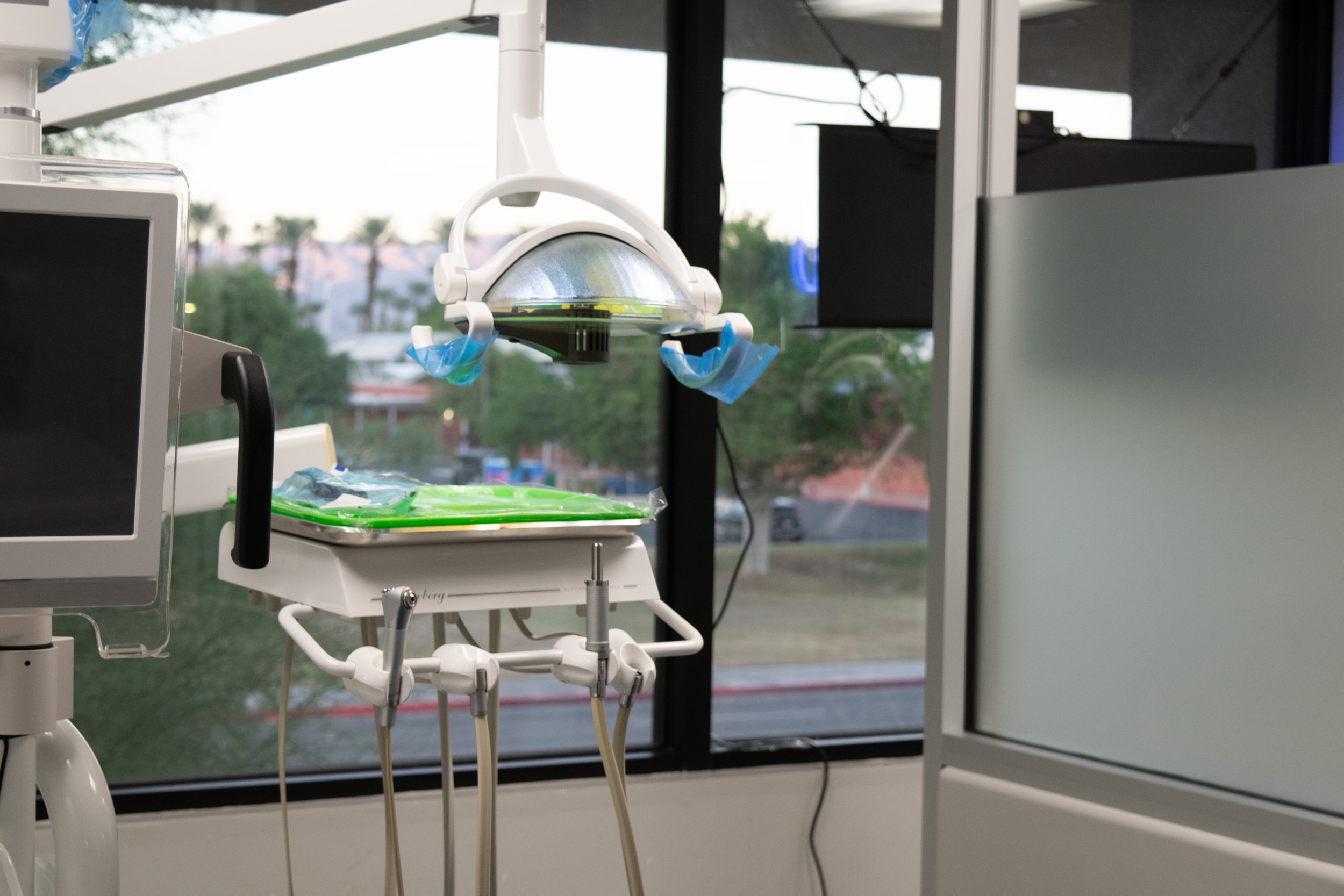 Dental surgical light, monitor, and sterilization equipment in a modern dental office with large windows.