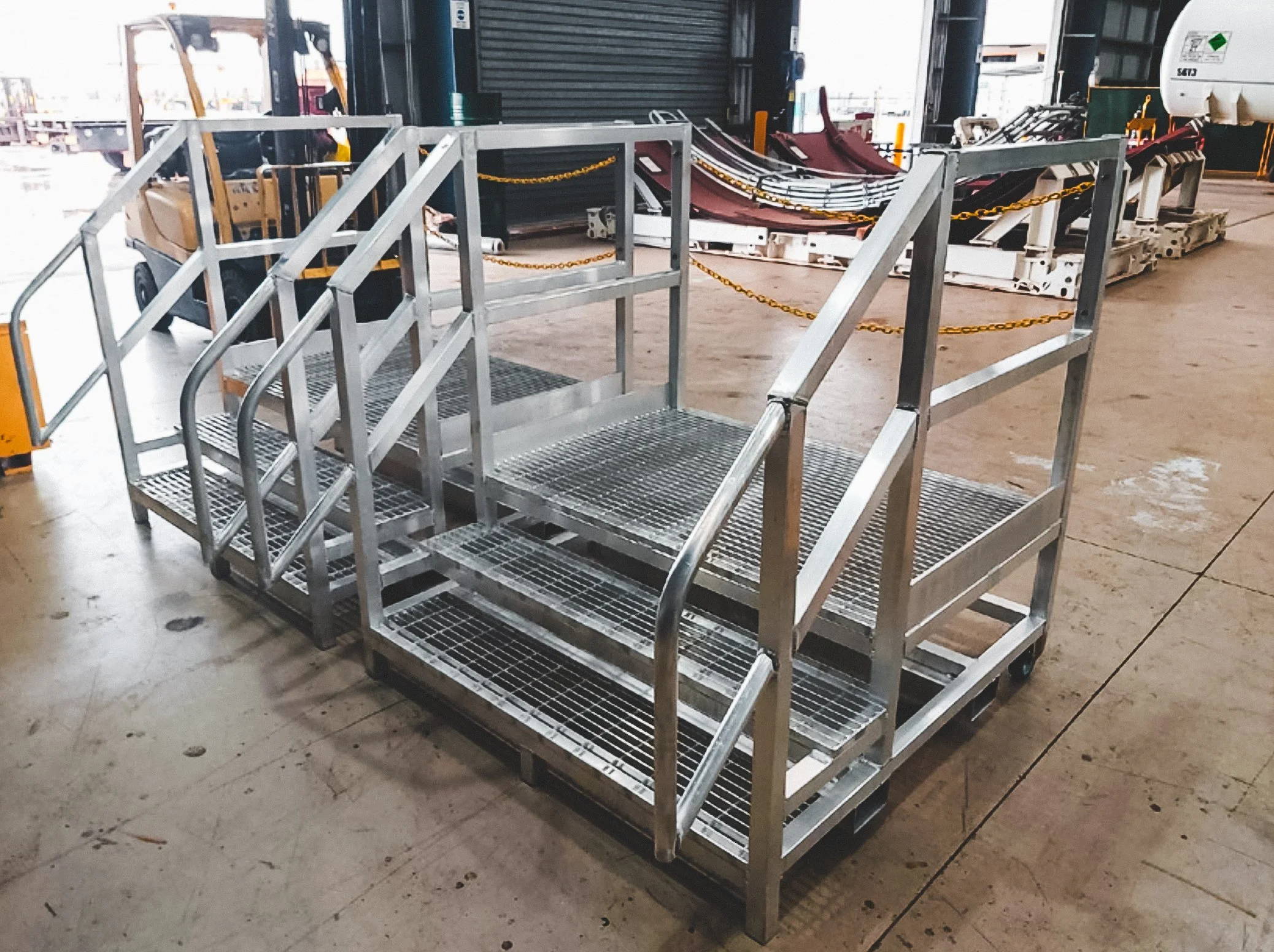 Metal rolling stairs and carts in an industrial warehouse.