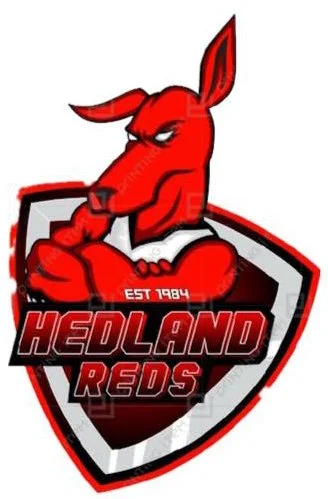 A red kangaroo mascot with crossed arms, standing in front of a shield-shaped background with the text 'Hedland Reds' and 'Est 1984'.