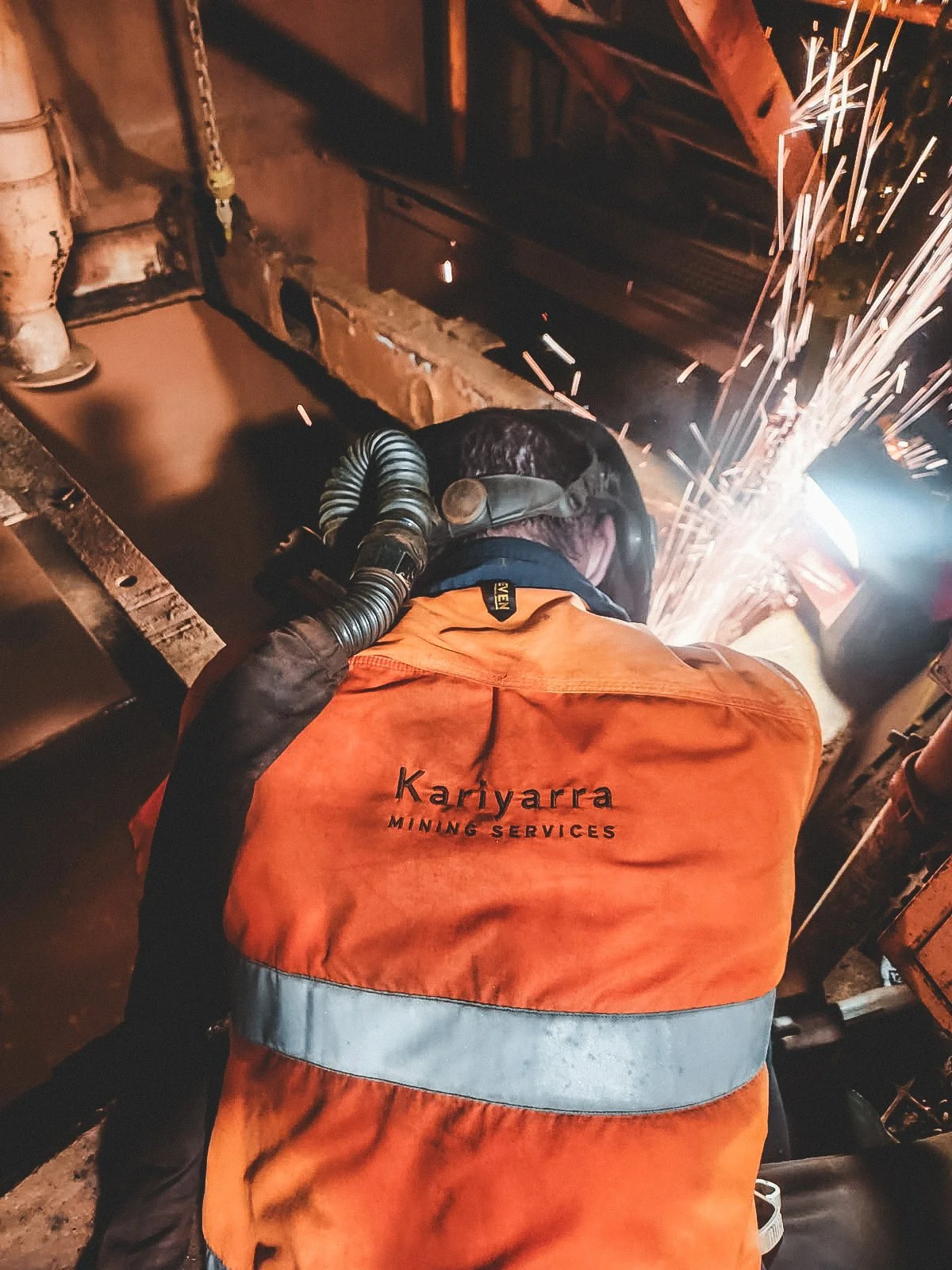 A worker wearing an orange and gray jacket with