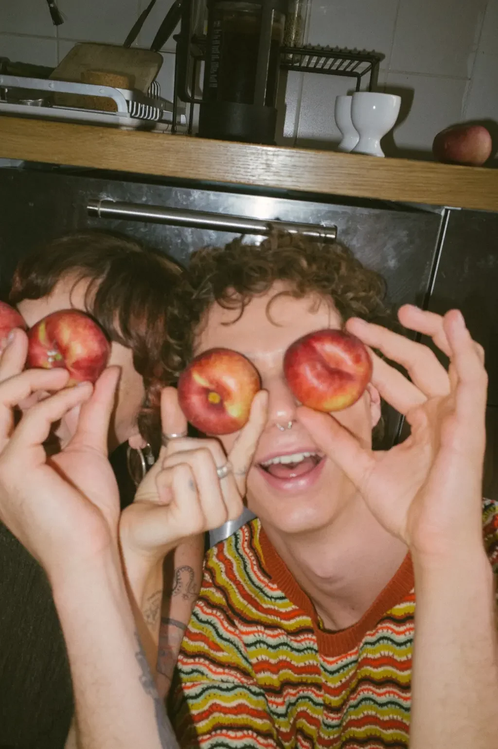 Friend holding apples over their eyes in a kitchen, the unmasked playfulness of finding your people with ADHD