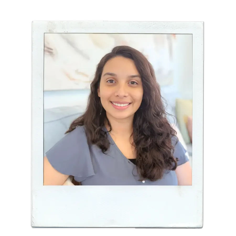 A modern house on a grassy hillside with snow-capped mountains in the background.