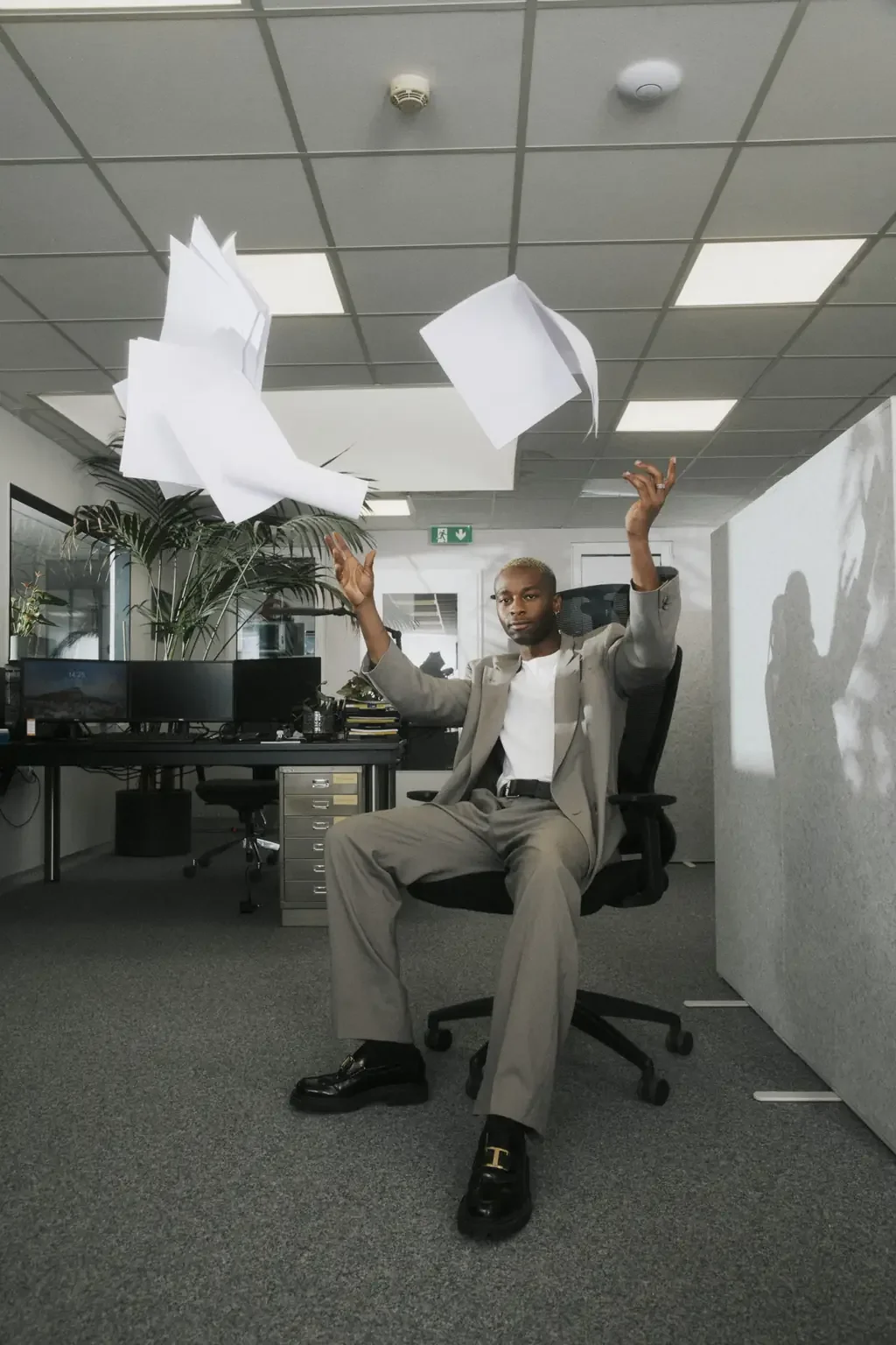 Office worker sitting back in a desk chair tossing loose papers into the air, done with the workday