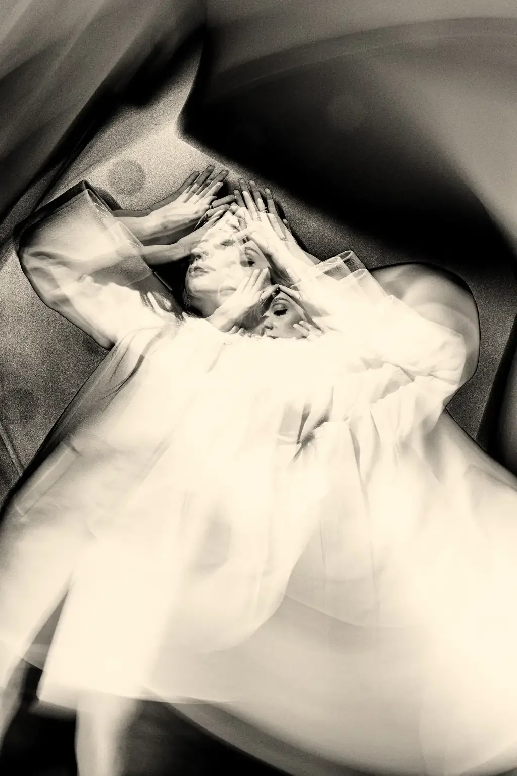 Multiple overlapping exposures of a woman in a white dress pressing her hands to her forehead, illustrating racing anxious thoughts with ADHD