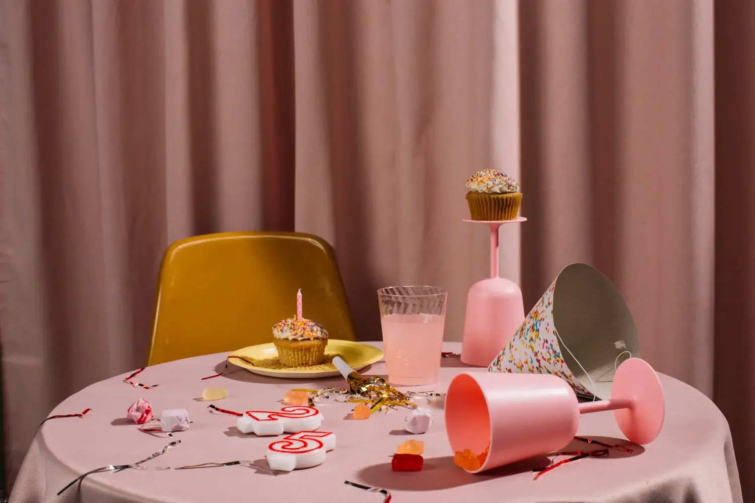 Empty birthday table with an untouched cupcake, a tipped-over glass, and scattered party streamers beside a vacant chair, evoking rejection sensitive dysphoria