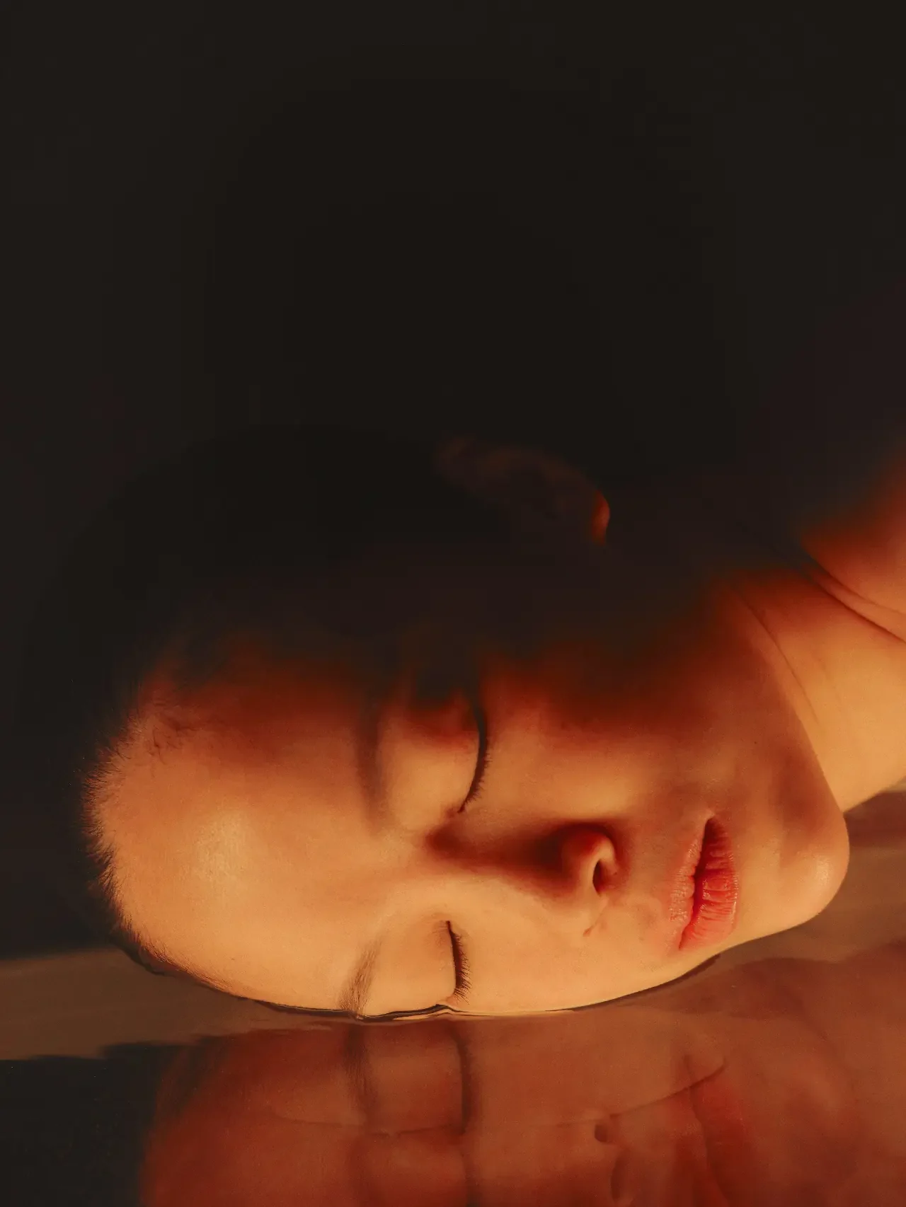 Woman resting with her eyes closed, her face at the surface of still water in warm amber light, a picture of rest that calms the nervous system.