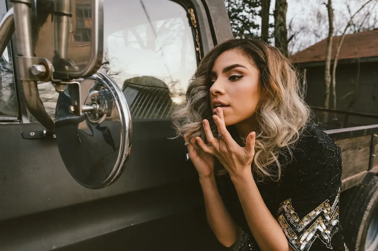 Woman checking her appearance in a vehicle side mirror before getting out, illustrating the pre-emptive self-checking that drives ADHD perfectionism.