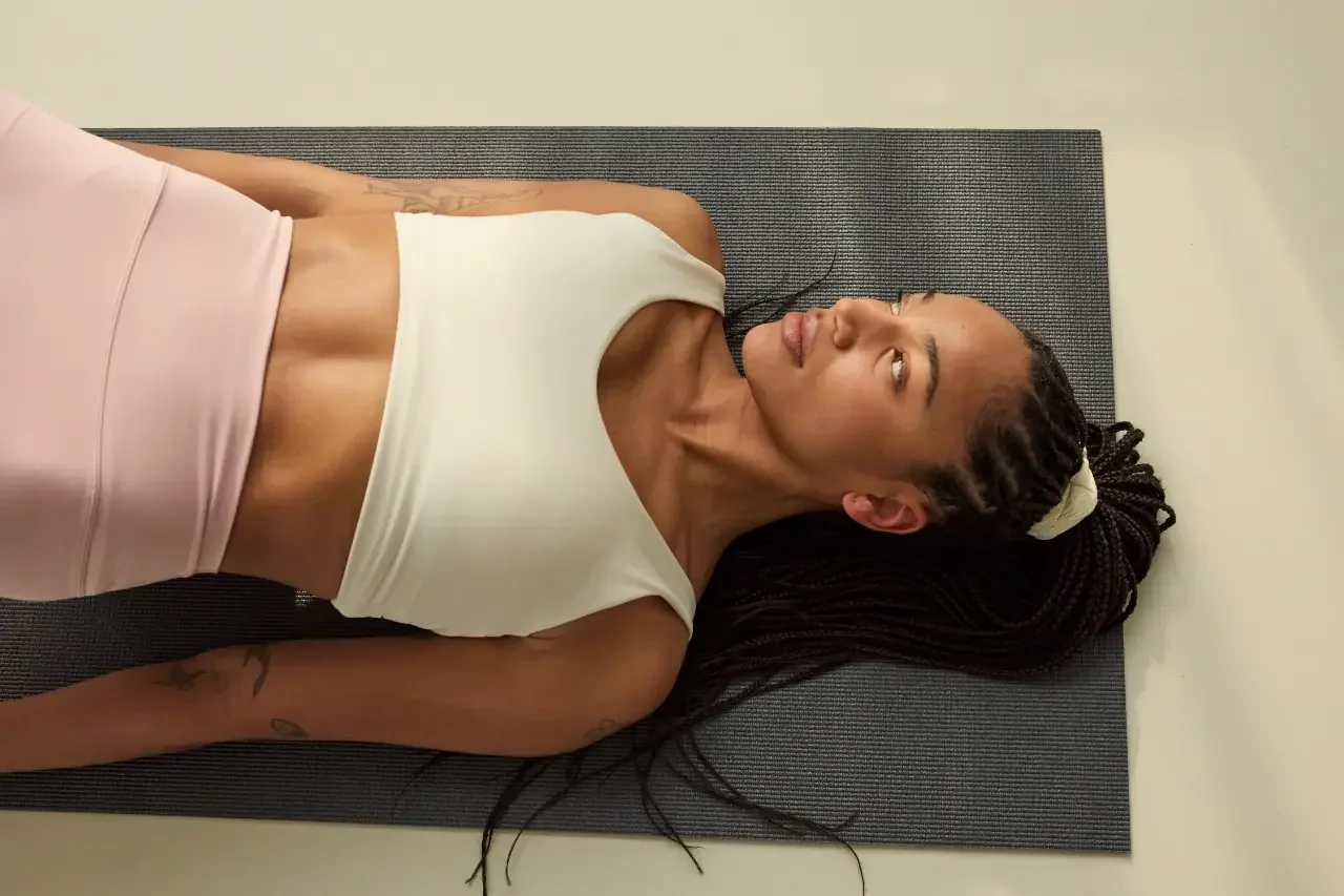 Woman lying on a yoga mat looking upward, pausing to notice anxious thoughts with ACT for ADHD
