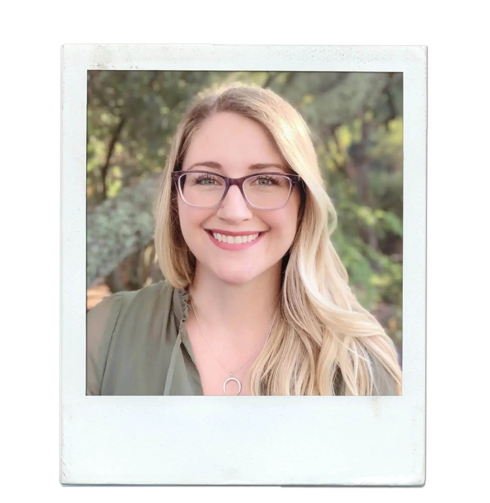 A smiling woman with long, blonde hair, wearing glasses and a green top, outdoors with trees in the background.