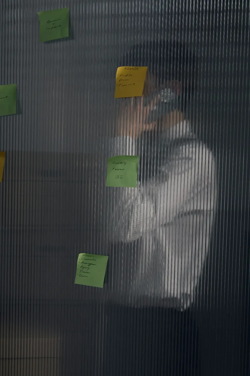 Person blurred behind textured glass with agenda sticky notes stuck to it, representing mental paralysis and brain fog with ADHD