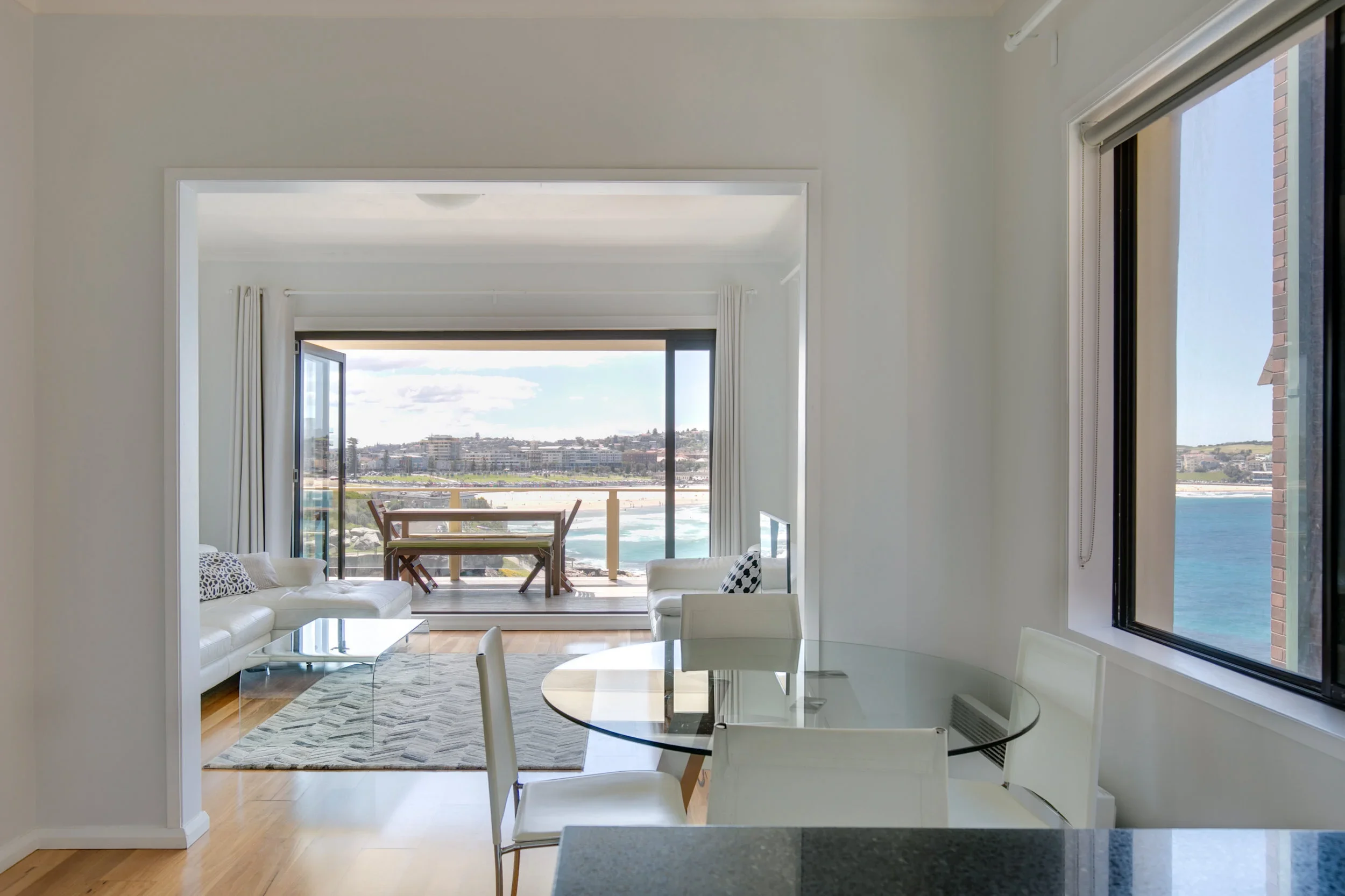 Living room and dining area with ocean view, white furniture, and large windows