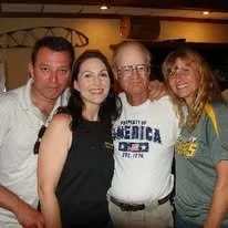 Four people standing together indoors, smiling for the photo.