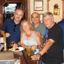 Group of five people enjoying drinks at a bar or restaurant table.