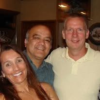 Three people smiling for a photo indoors, two men and one woman.