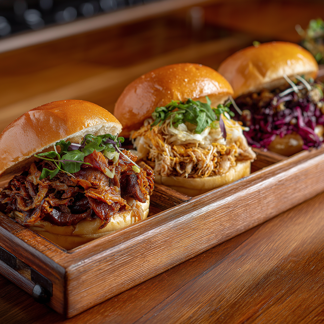 Trio of pulled meat burgers on wooden tray