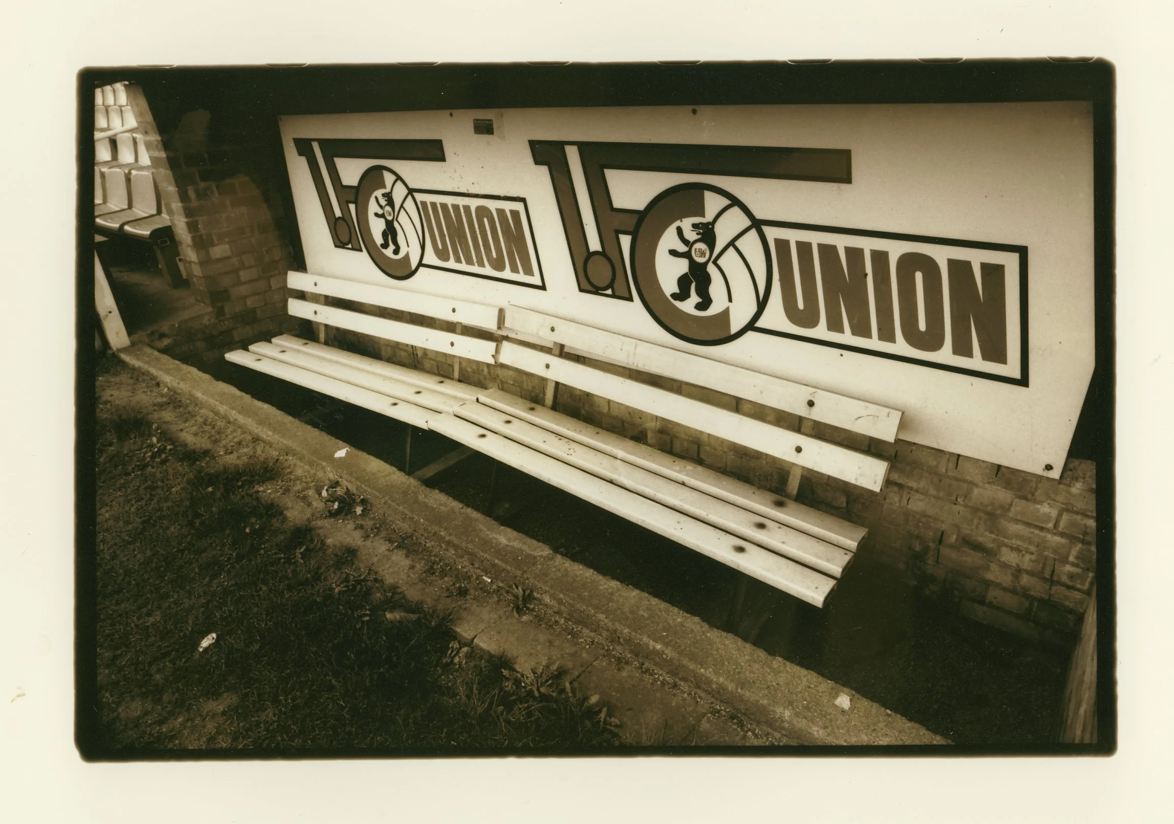 Empty wooden bench in front of a large sign with the word 'UNION' and a cartoon bear mascot symbol, outside a brick building.