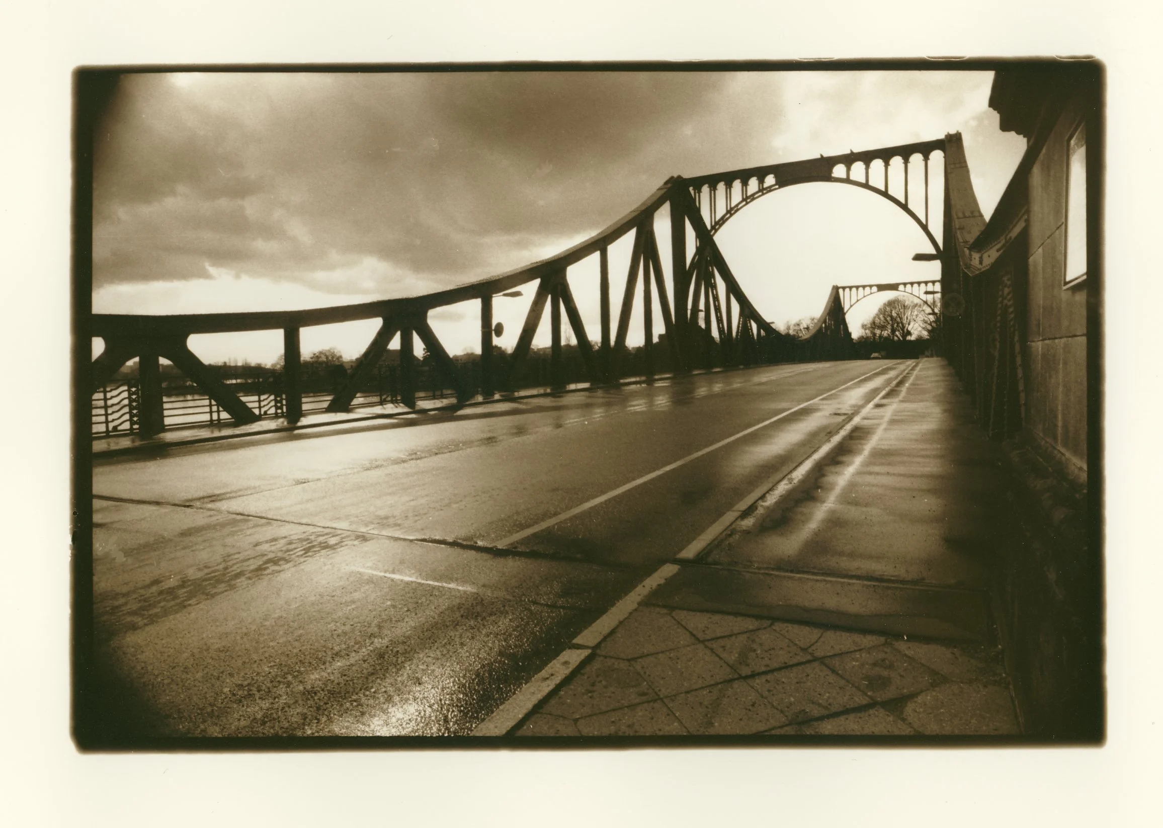 Black and white photo of a bridge with multiple arches and a road running underneath it.
