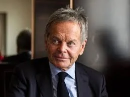 Homme d'âge moyen en costume, dans un environnement intérieur, probablement un bureau.
