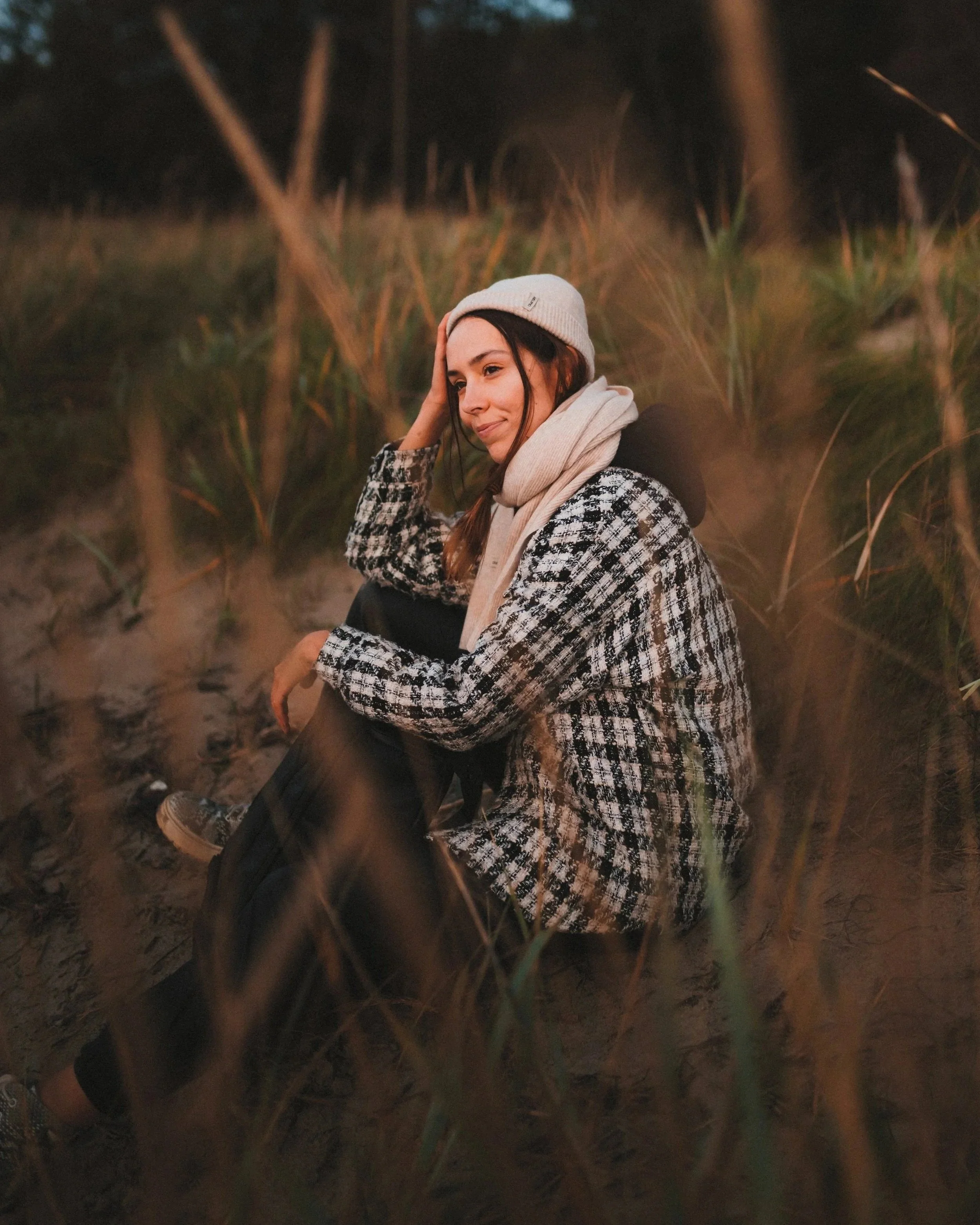 A photo of a girl wearing Craftory hat and scarf, sitting in nature