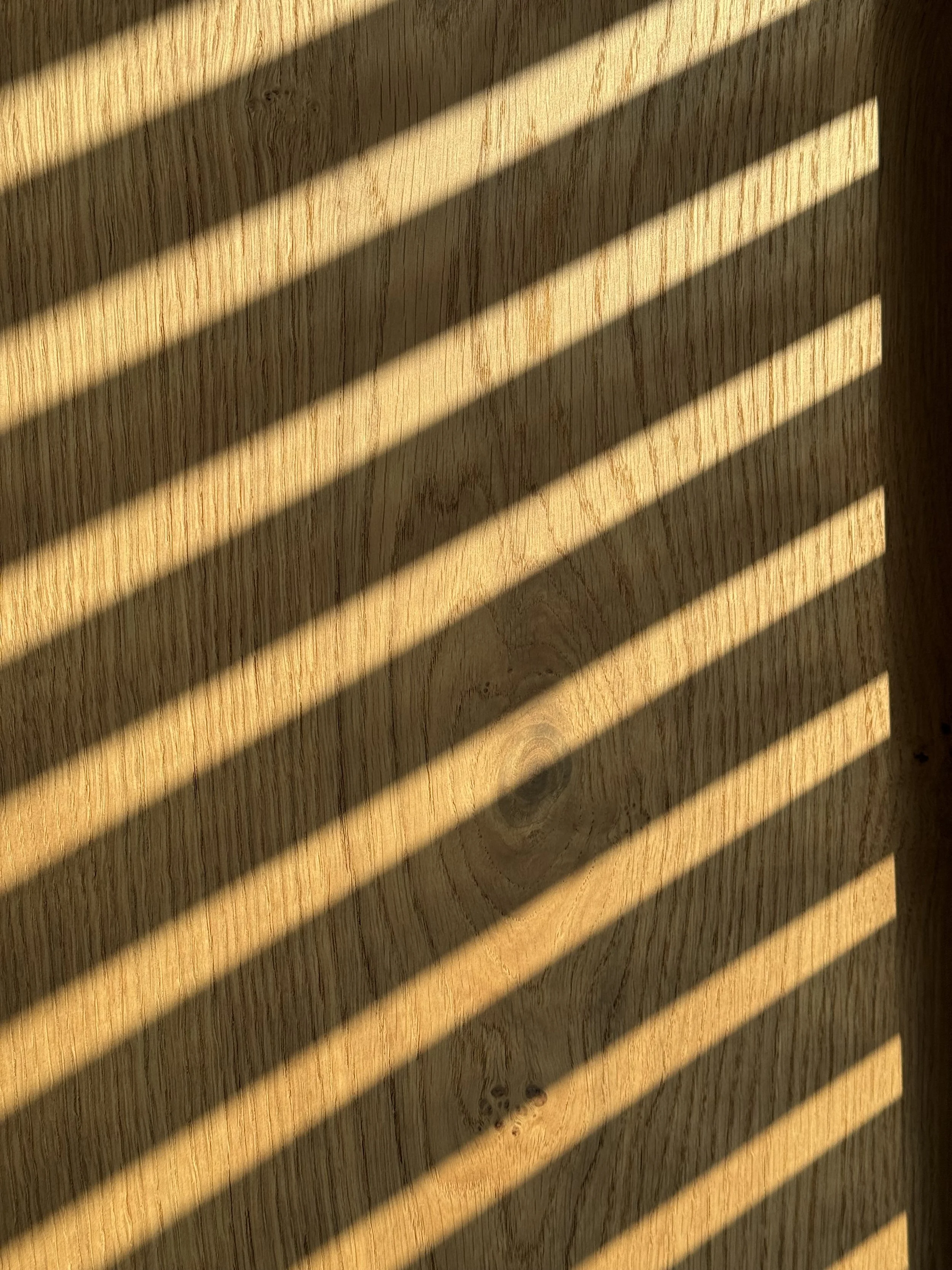 Schatten von Jalousien auf einer Holzoberfläche