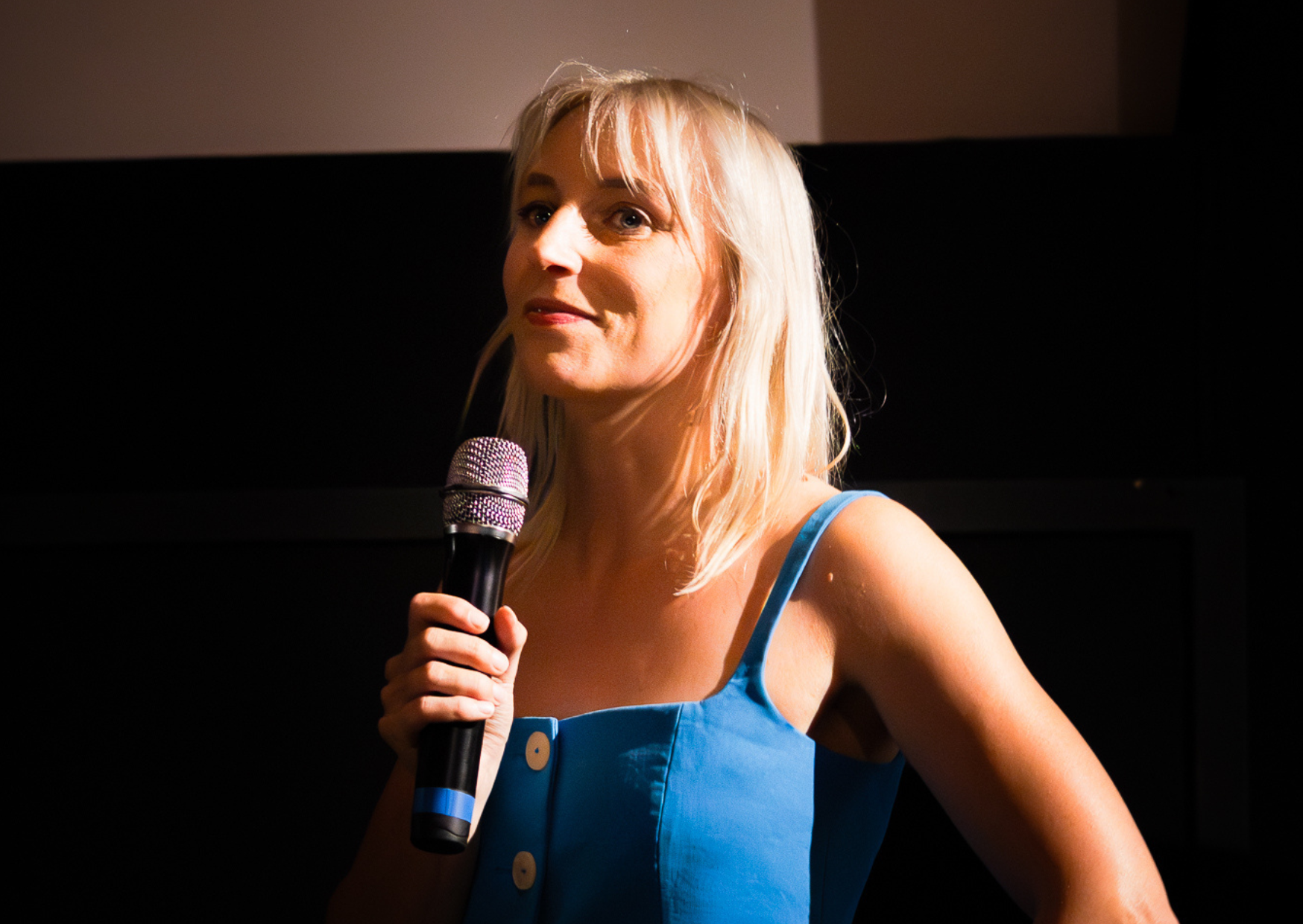 Dide Vonk op haar podcastlancering met een microfoon in haar hand