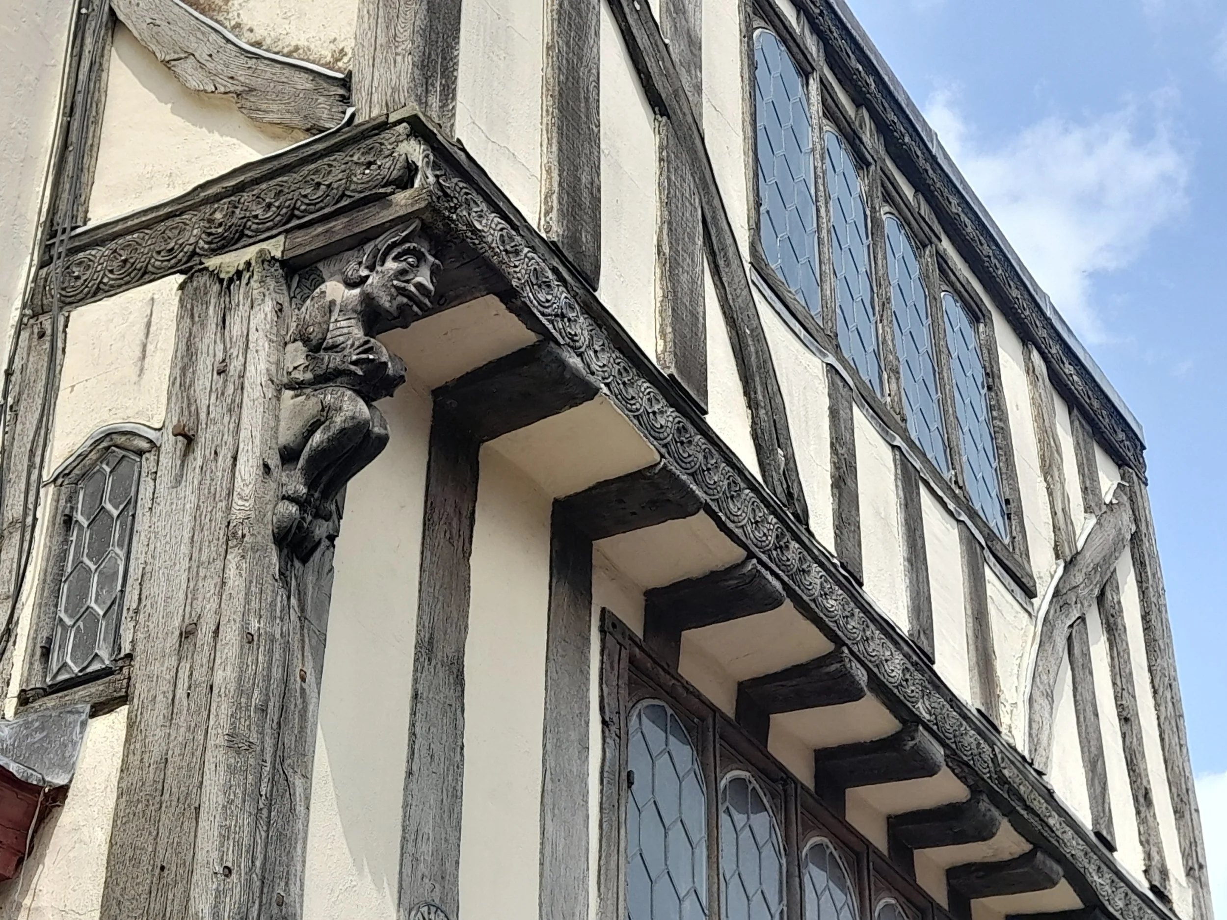 Carved corbel statue on exterior of historic house at 8 Palace Street, Canterbury, depicting a figure supporting the timber-framed structure.
