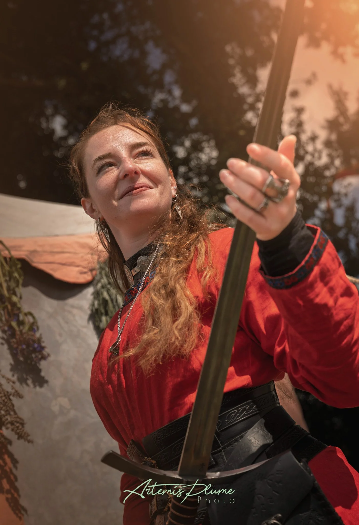 Photo d'une femme en robe viking rouge, portant une épée