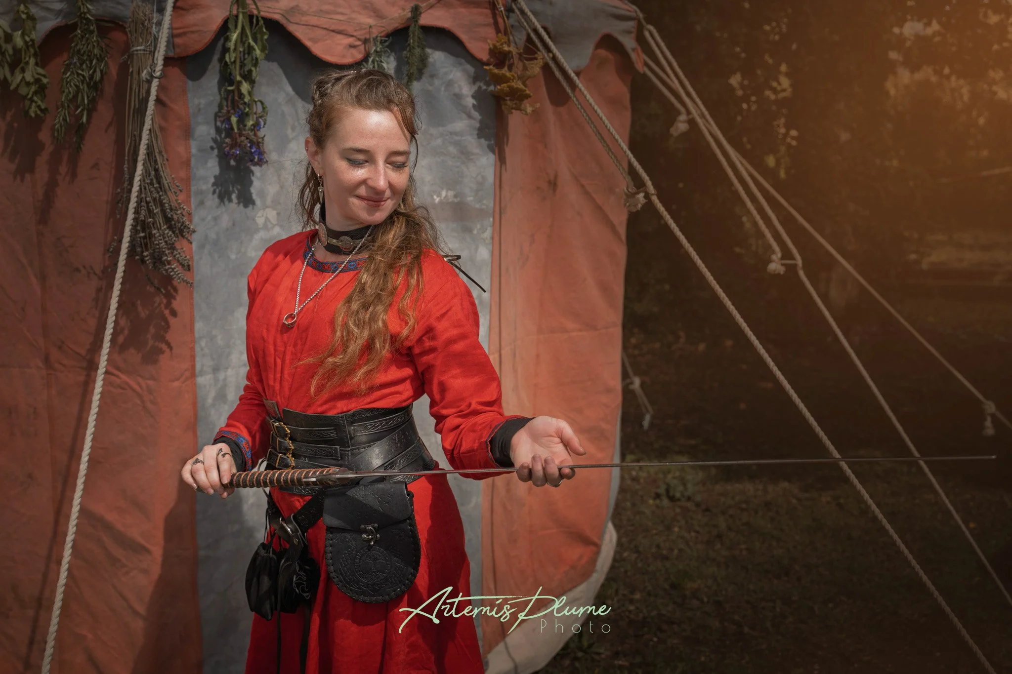 Photo d'une femme en robe viking rouge, portant une épée