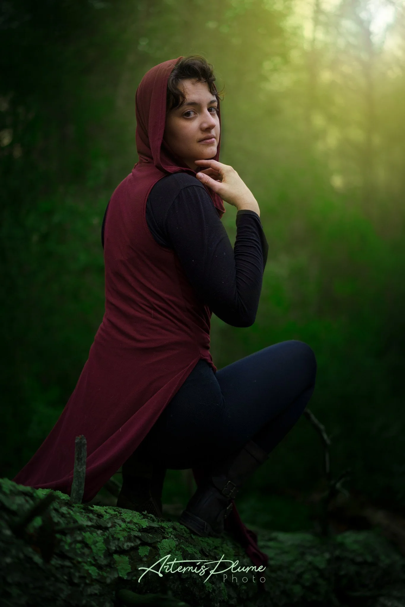 Photo d'une femme avec capuche rouge accroupie dans une forêt