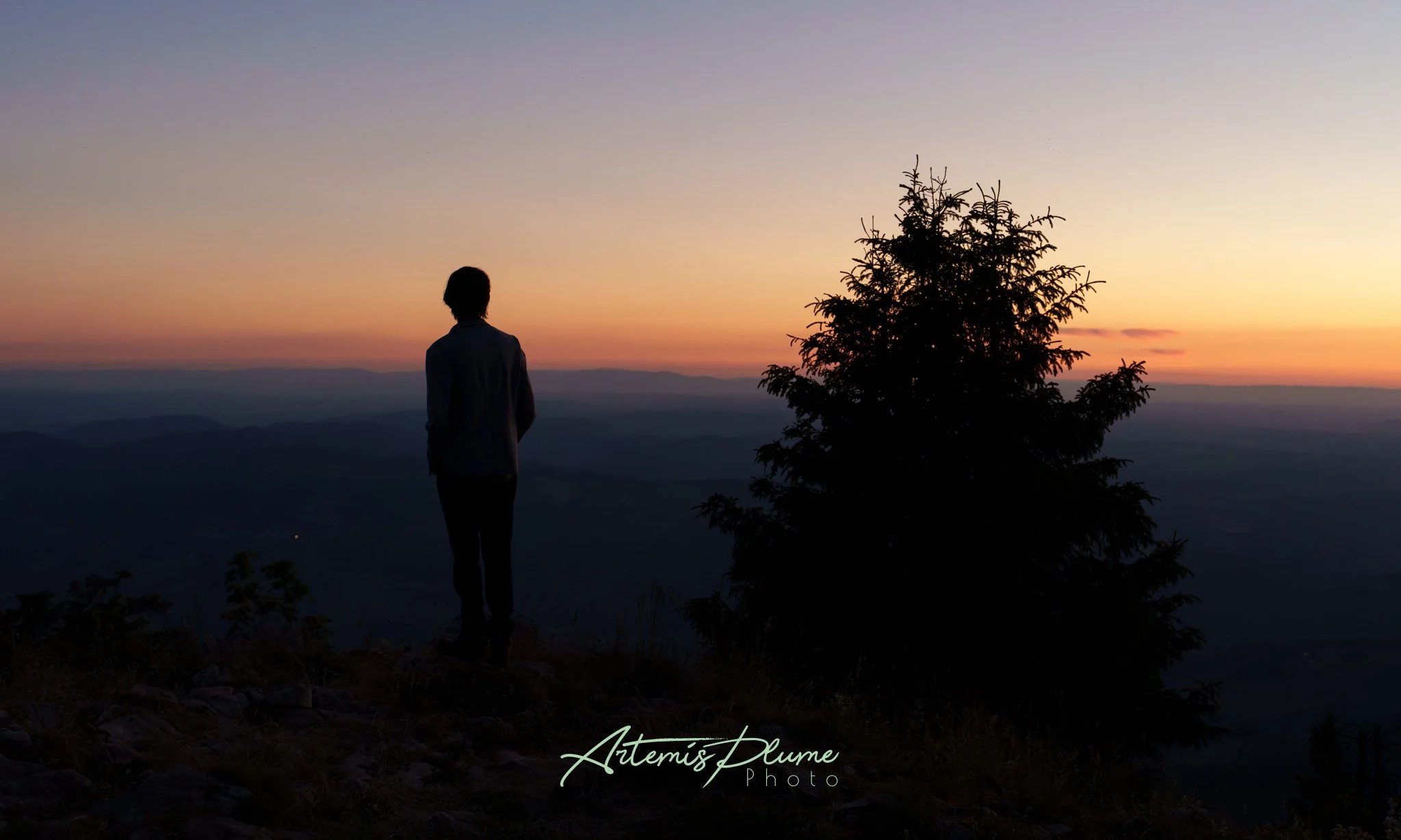 Silhouette d'une personne regardant le coucher du soleil depuis un sommet 