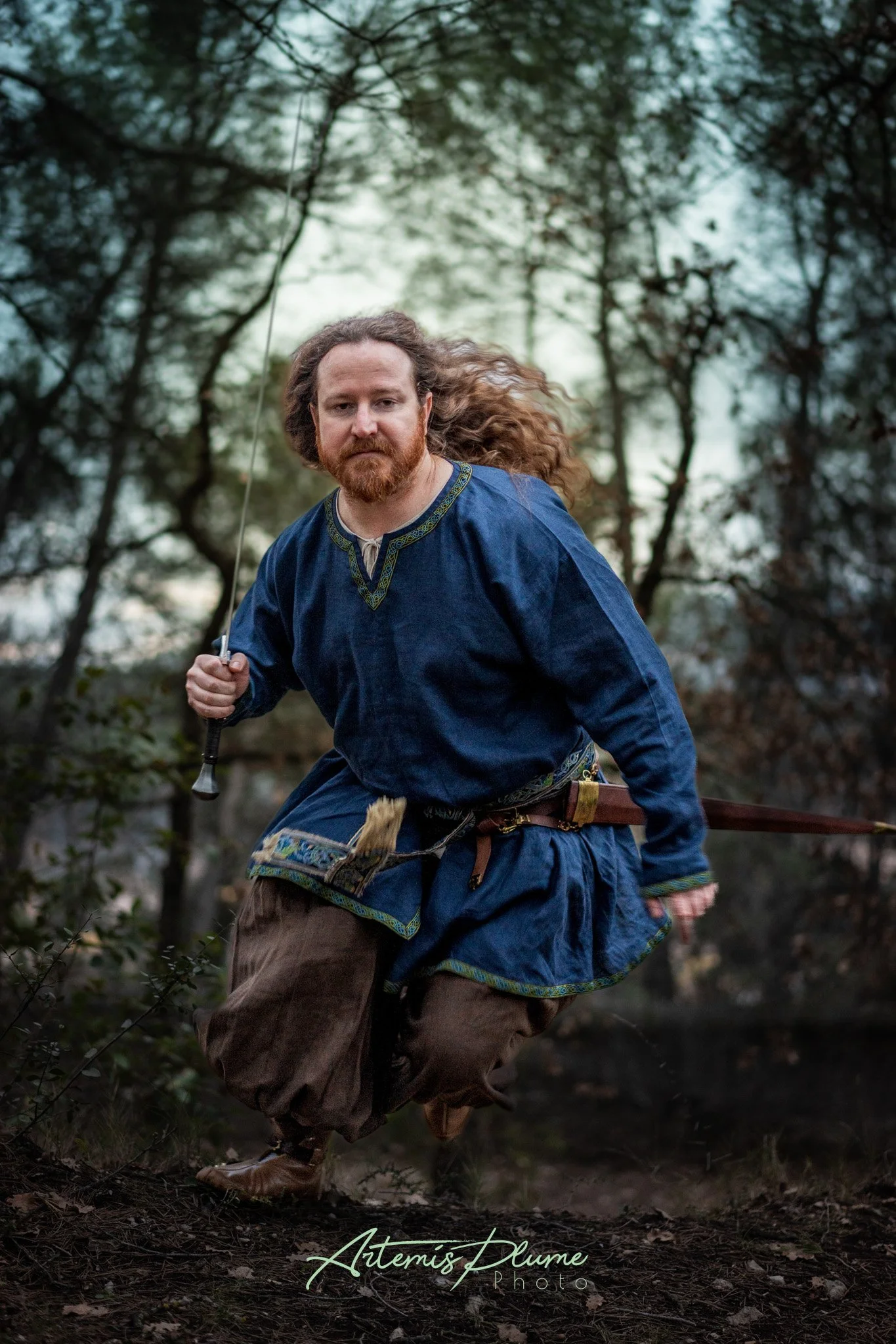 Photo d'un homme en costume médiéval courant vers la caméra, épée dégainée 