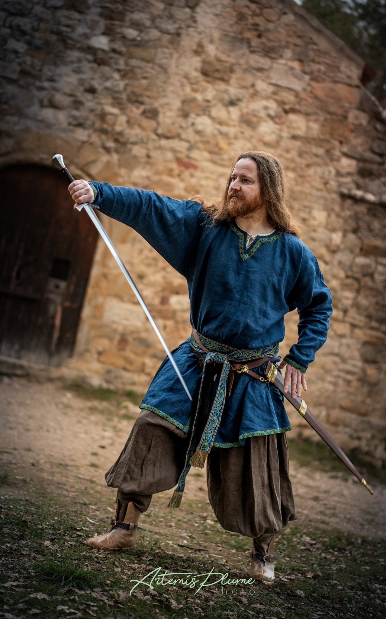 Photo d'un homme en costume médiéval préparant son épée