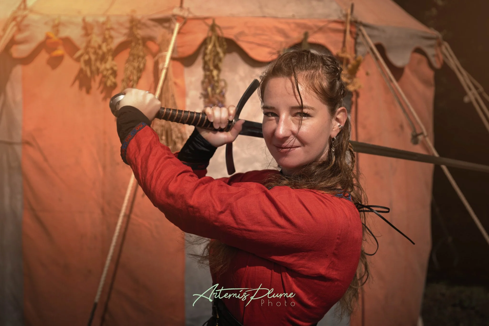 Photo d'une femme en robe viking rouge, portant une épée