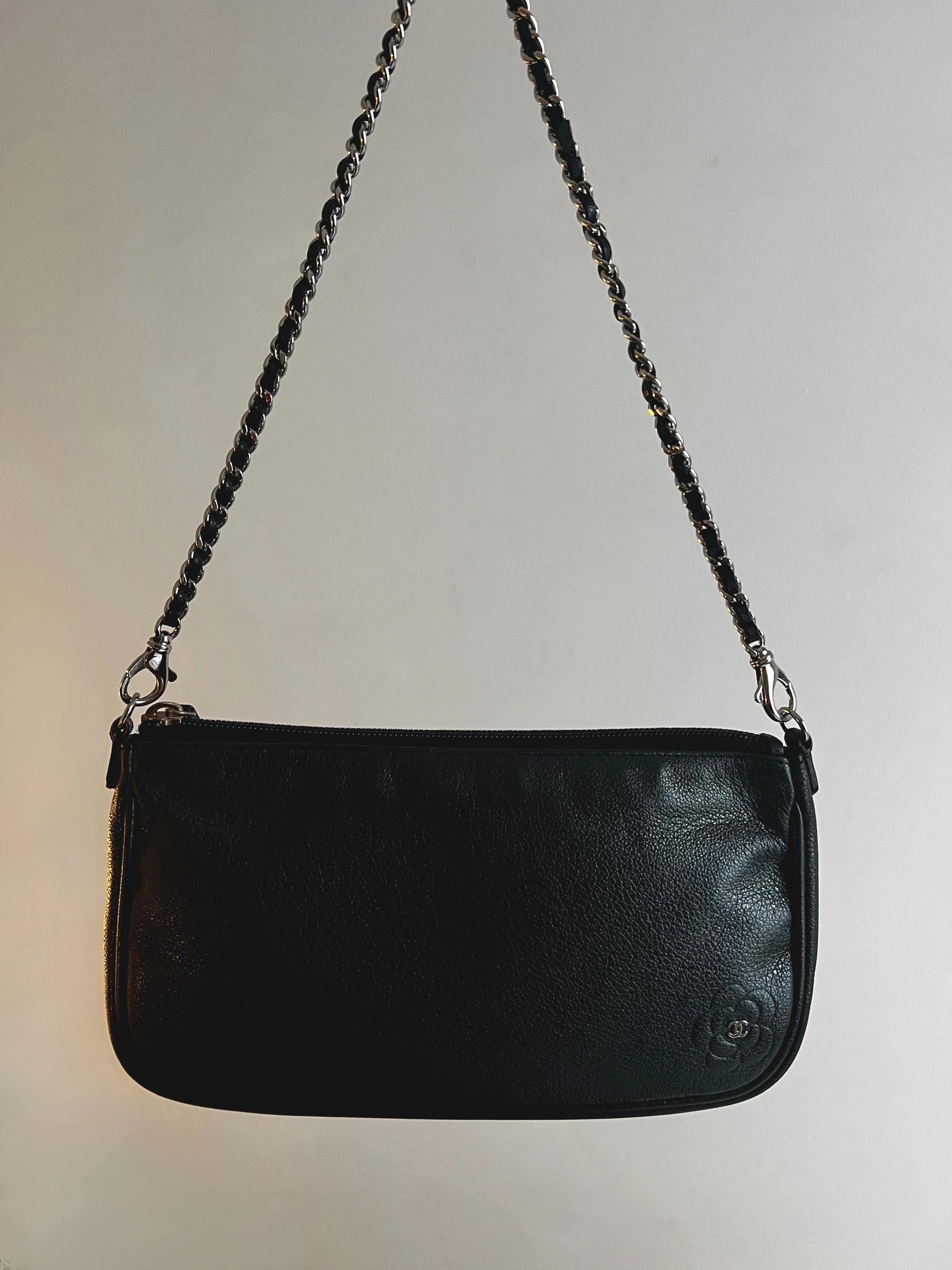 Black designer handbag with chain strap against a plain background.