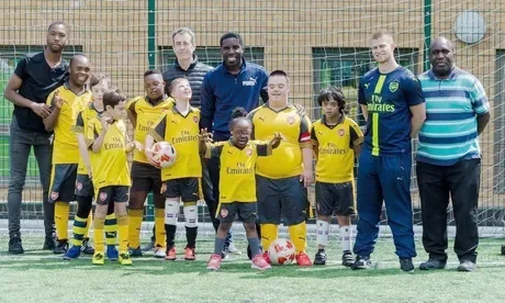 The image shows a group of children with Down Syndrome dressed in football attire with their coaches