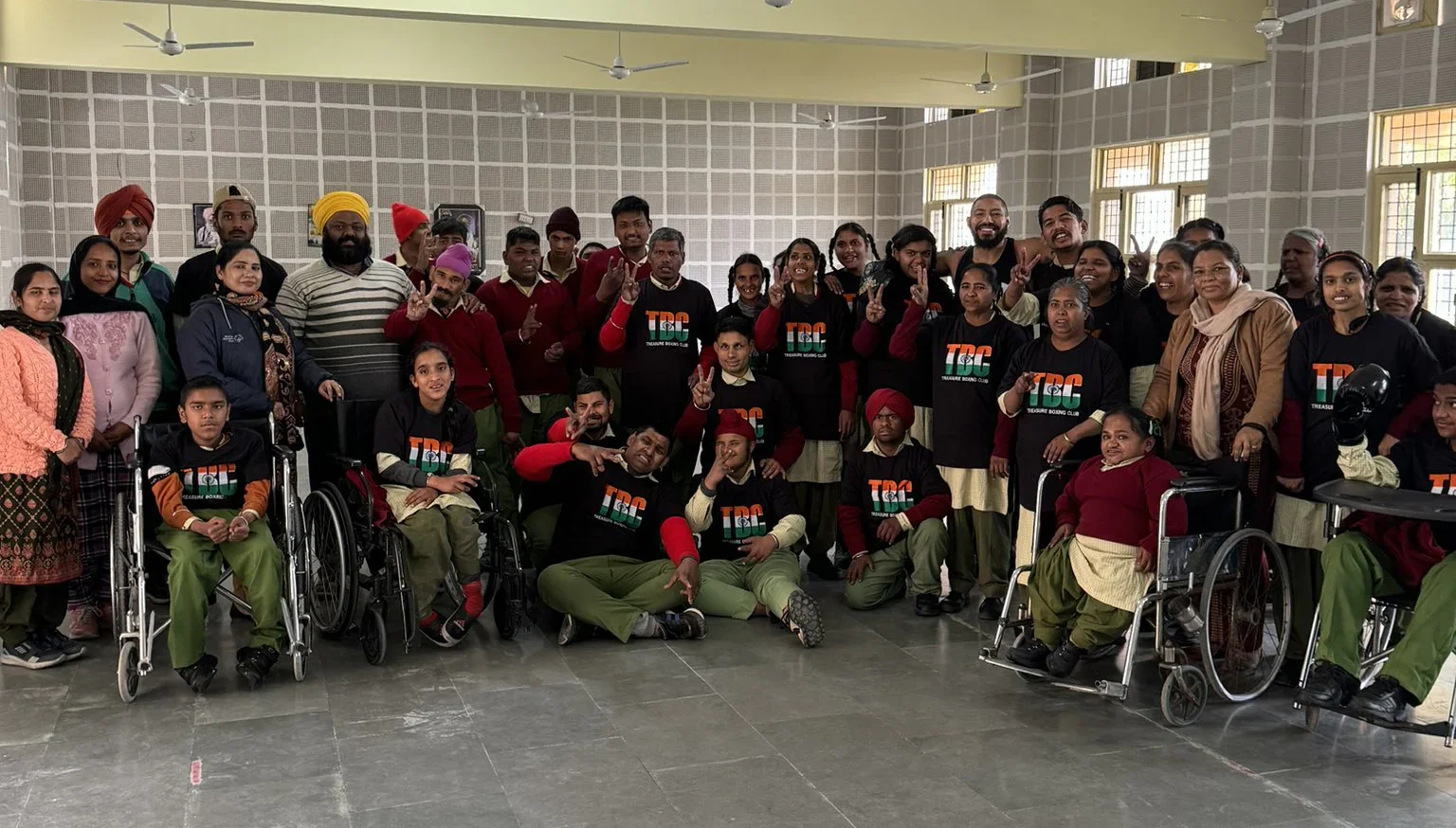 The photo shows a large group of people some are standing and some are seated in wheelchairs