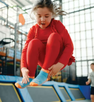 The image shows a child jumping on a trampoline with their legs tucked up
